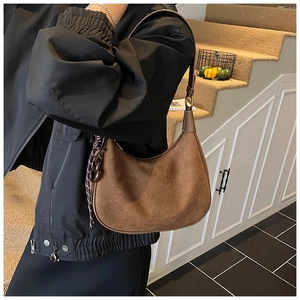 Sac hobo en daim marron porté par un mannequin avec une forme de croissant et un style rétro