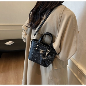 Detail of black crossbody bucket bag featuring diamond print and dog-shaped charm pendant