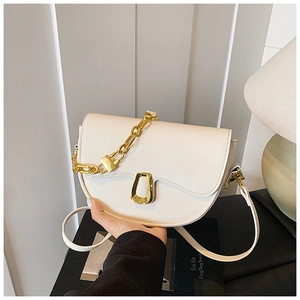 Detail of creamy white saddle bag with golden chain and U-shaped metal buckle finish