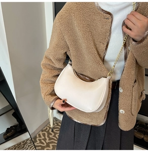 Chic beige half-moon hobo bag with a delicate gold chain strap shown on a model