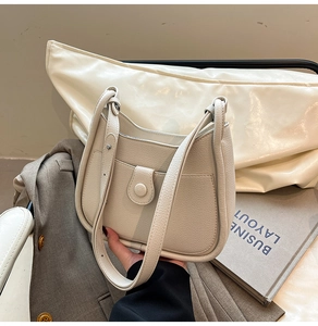 Detail of off-white lychee leather shoulder bag with adjustable strap in business setting