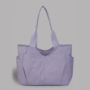 Detail view of a lavender nylon tote bag featuring front pockets and wide shoulder straps