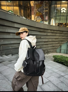 Detailed view of black leather backpack with drawstring closure and vintage flap design