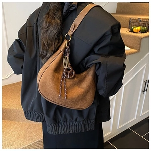 Sac hobo en daim marron avec breloque boulier et détails de corde porté par le modèle