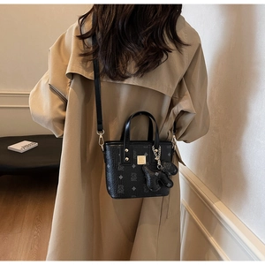 Detail of black vintage bucket bag with monogram pattern and golden logo plate