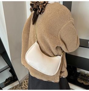Model wearing a stylish cream half-moon hobo bag with a gold chain strap and smooth texture