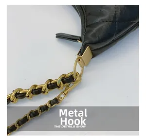 Close-up of black quilted leather texture and gold metal chain hook on crossbody bag