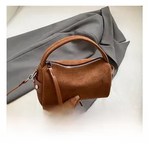 Dettaglio della trama della borsa a cilindro in camoscio marrone con zip argento
