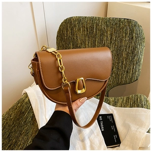 Detail of caramel half-moon saddle bag featuring gold chain and shield buckle closure
