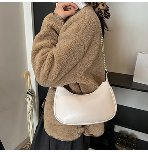 Chic cream semi-circle shoulder bag with elegant gold chain strap worn by a model