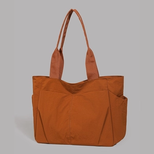 Burnt orange large capacity tote bag featuring dual front pockets and side compartments