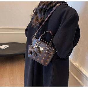 Detail of brown leather bucket bag with logo pattern paired with a black winter coat