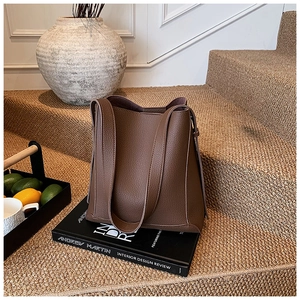 Detail of dark brown lychee textured leather bucket bag on an interior design book