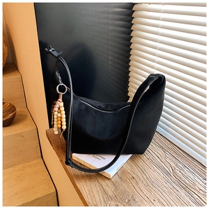 Detail einer schwarzen Hobo-Tasche aus Wildleder mit verstellbarem Riemen und Holzperlen