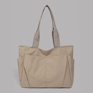 Detail showing khaki tote bag with dual front pockets and lightweight nylon texture
