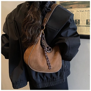 Détail du sac hobo en daim marron avec bandoulière en cuir et pendentif pompon tissé