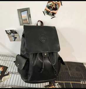 Detailed macro view of the black faux leather texture and embossed logo on the backpack