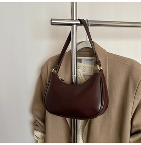 Detailed view of dark brown crescent bag with smooth glossy leather and gold hardware