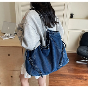 Dettaglio macro della fibbia laterale in metallo e del tessuto denim lavato della borsa tote