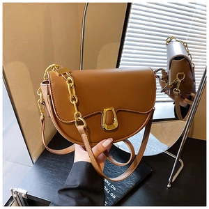 Detail of brown PU leather saddle bag featuring a gold U-buckle and thick metal chain strap