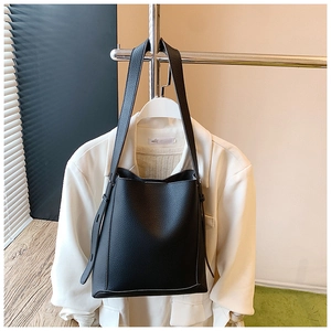 Close-up of black litchi pattern leather texture on a minimalist bucket shoulder bag