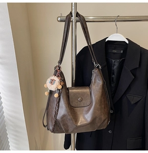 Detail of dark brown faux leather tote bag with vintage texture and sheep plush charm