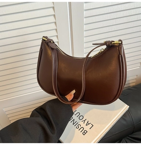 Detail of dark brown semi-moon hobo bag with PU leather texture and gold hardware