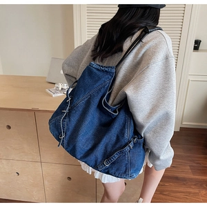 Dettaglio della borsa tote in denim con fibbie in metallo e tracolle in pelle nera