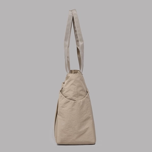 Detail view of the side pocket and nylon texture on the light khaki tote bag