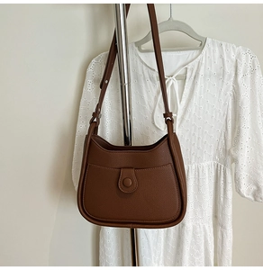 Detail view of brown lychee grain hobo bag with front magnetic pocket on metal stand