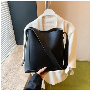 Close-up of black lychee texture leather bucket bag with wide shoulder strap details