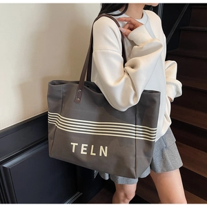 Detail view of large grey canvas tote bag with white stripes and brown leather straps
