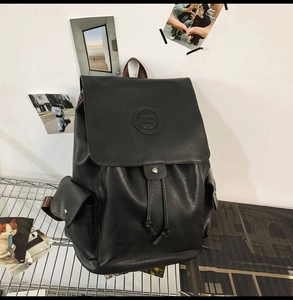 Detail of vintage black faux leather backpack with drawstring closure and buckled side pockets