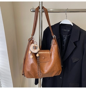 Detail of a brown PU leather tote bag with metallic zipper and a cute lion plush charm