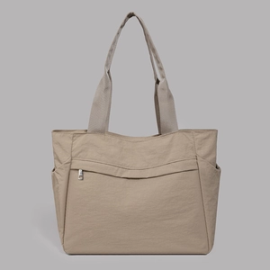 Close-up of khaki nylon tote bag featuring front zipper pocket and side open pouches