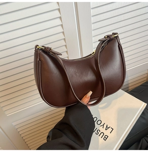 Detailed view of deep brown crescent shoulder bag with golden metallic buckle and smooth finish