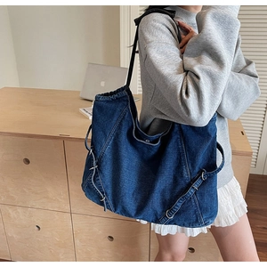Dettaglio ravvicinato di una borsa tote in denim blu con cuciture diagonali e fibbia in metallo
