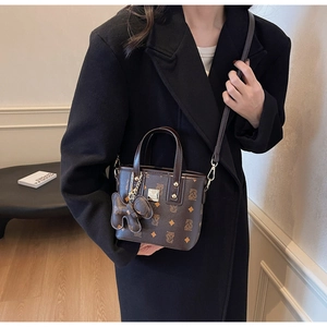 Brown vintage bucket bag detail with monogram pattern and cute bear charm accessory