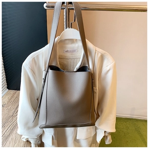 Detail of taupe litchi grain leather bucket bag showing side straps and texture