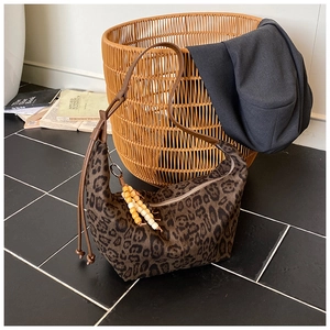Detail der sichelförmigen Tasche mit Leopardenmuster, Lederriemen und Holzperlenanhänger