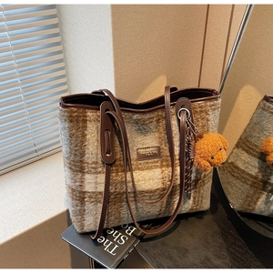 Détail du sac cabas en laine avec motif à carreaux marron et un joli pendentif ours