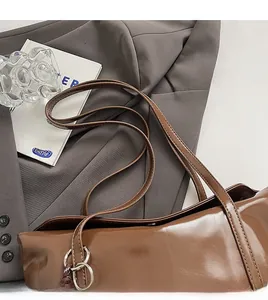 Detail of glossy brown wax leather tote with metal buckle and shoulder strap