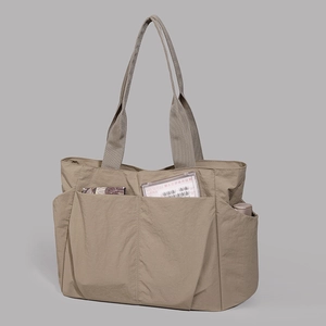 Detail view of khaki large capacity tote bag featuring functional front pockets and nylon fabric