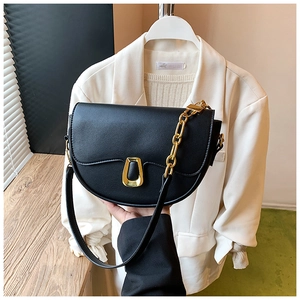 Close-up of black leather saddle bag with distinctive gold metal buckle and chunky chain