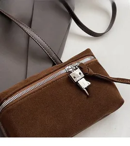 Detail view of brown suede crossbody bag with a robot metal charm and silver zipper