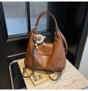 Detail view of a vintage brown tote bag with plush charm and matte texture on books