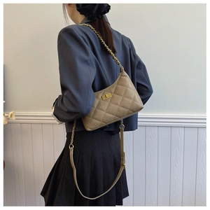 Detail of quilted coffee chain bag with vintage gold turn-lock on a model shoulder