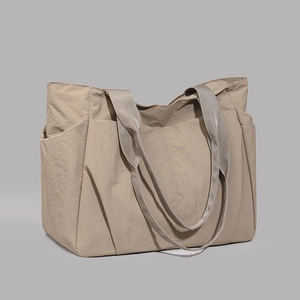 Detail of khaki nylon tote bag showing side pocket texture and reinforced webbing handle