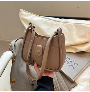 Close-up of brown pebbled leather handbag with curved design and stylish buckle detail