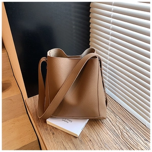 Detailed view of caramel brown litchi pattern leather bucket bag with wide shoulder strap